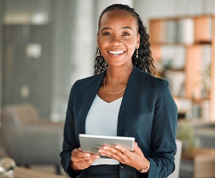 Woman smiling while holding tablet in office