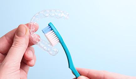 Patient cleaning clear aligner with toothbrush