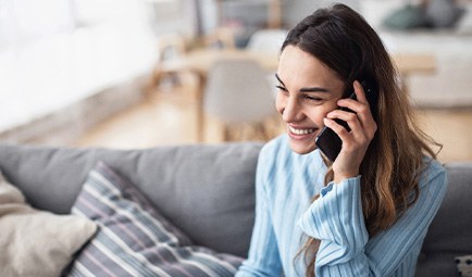 Woman smiling while talking on phone on couch
