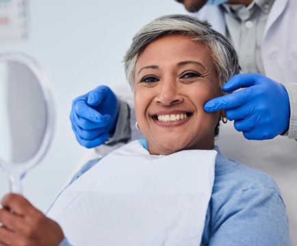 Dentist pointing to his patient’s smile after cleaning appointment 