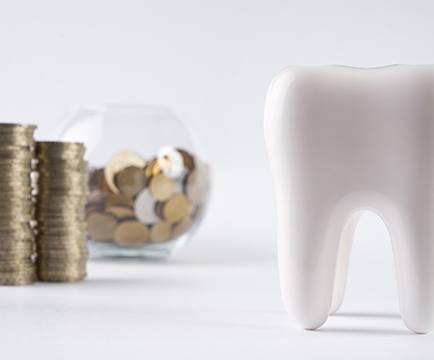 Tooth next to a pile of coins