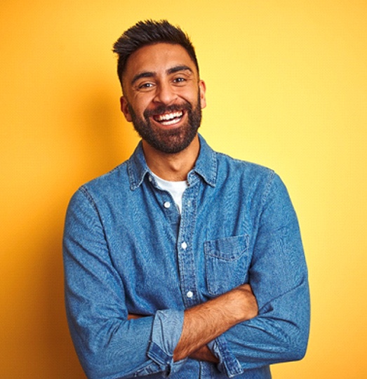 Man smiling with dental crowns in Baltimore and arms crossed