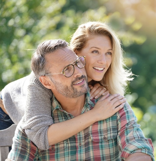 Man and woman smiling after dental implant tooth replacement