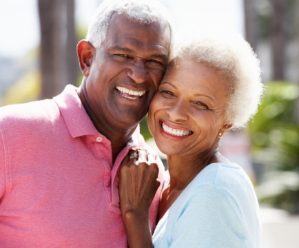 Man and woman smiling after dental implant tooth replacement