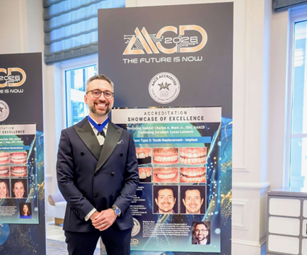 Dr. Ward posing in front of a banner with a dental case of his on it