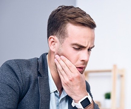 Man in need of emergency dentistry holding jaw