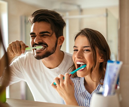 Man and woman brushing teeth to prevent dental emergencies