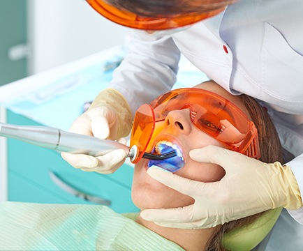 Dentist hardening woman’s filling with ultraviolet light