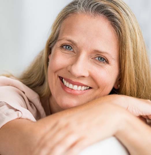 Middle-aged woman smiling after full mouth reconstruction in Baltimore