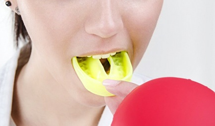 person putting a yellow mouthguard in their mouth