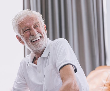 A smiling, older man happy with his new implant dentures