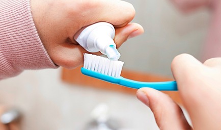 Woman putting toothpaste on a toothbrush