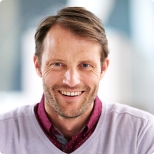 Man wearing white cardigan and smiling