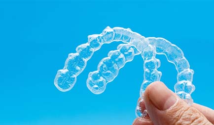 person holding two Invisalign aligners