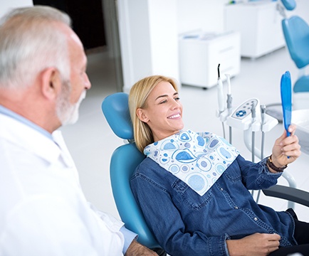 Doctor Murphy smiling at dental patient as she looks at her smile