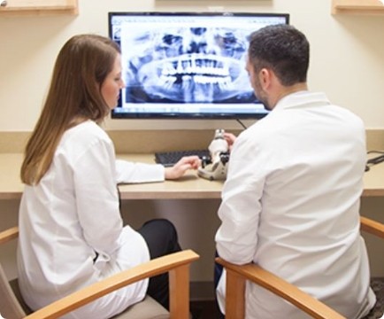 Two dentists looking at digital x-rays and smile model