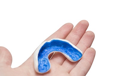 Patient holding blue and white mouthguard
