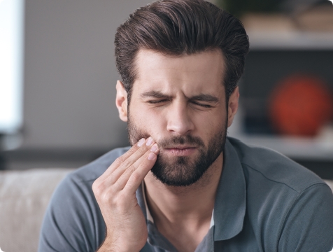 Man in need of emergency dentistry holding jaw in pain