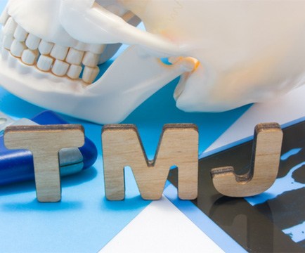“TMJ” in cardboard letters in front of model of skull; TMJ treatment in Baltimore, MD