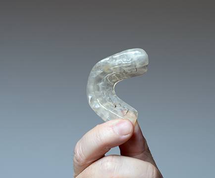 Hand holding a clear occlusal splint