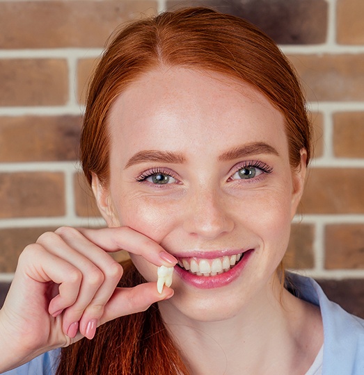 Woman holding tooth after visiting a dentist in Baltimore