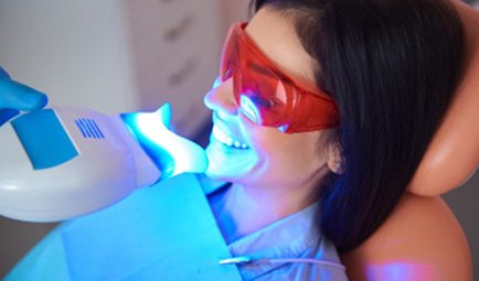Woman smiling during in-office teeth whitening treatment