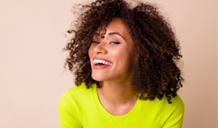 Woman with white teeth smiling in neon shirt