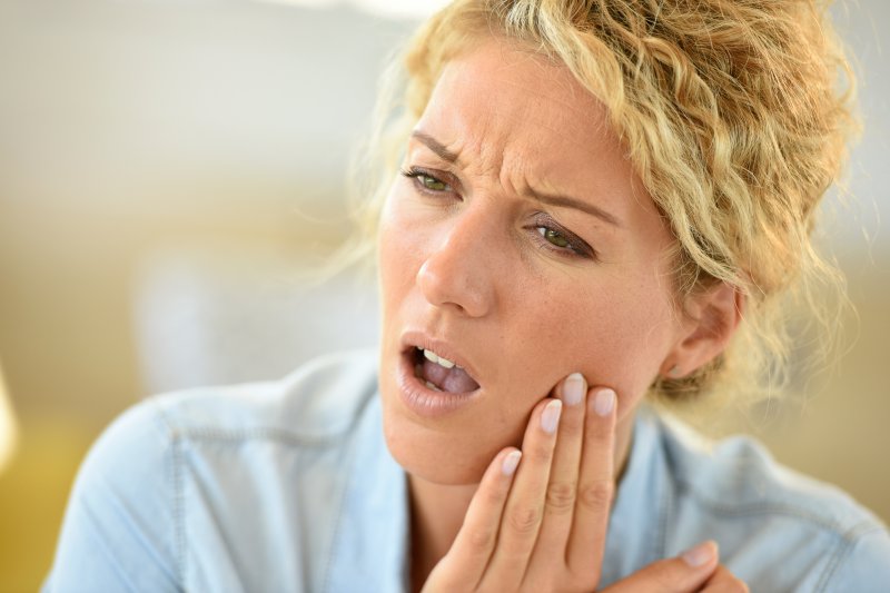 person holding their jaw and wincing