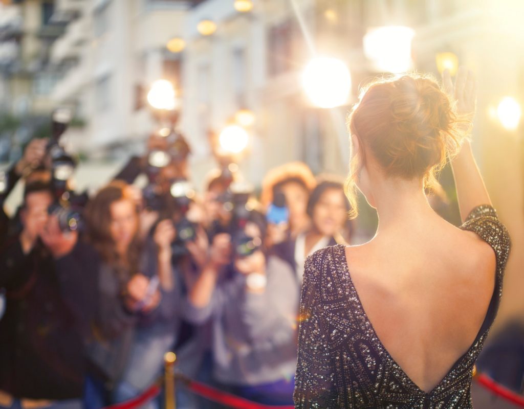 Celebrity waving at photographers on red carpet