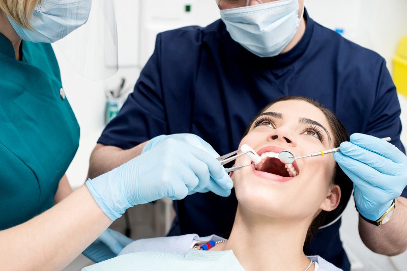 A young woman receiving a dental checkup from her dental team
